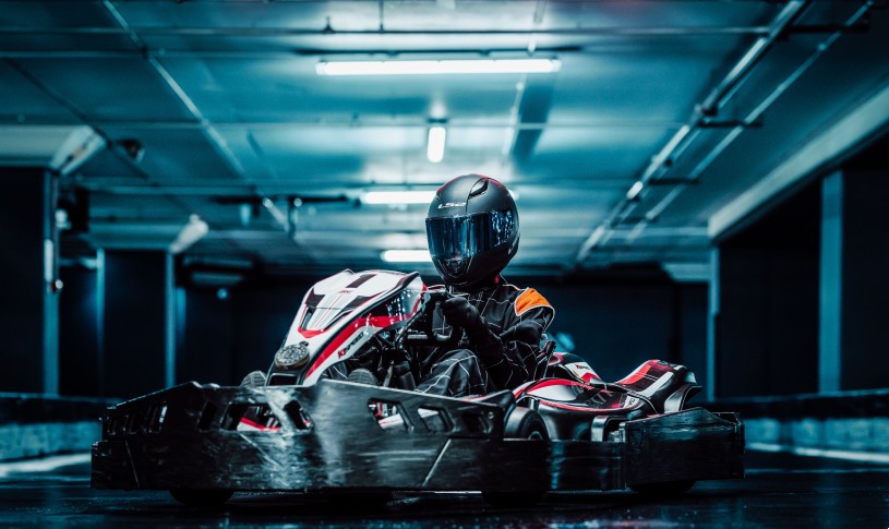 Racer driving a high-speed go-kart indoors on a modern track